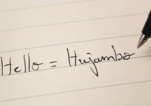 beginner-swahili-language-learner-writing-hello-word-hujambo-for-homework-on-a-notebook-macro
